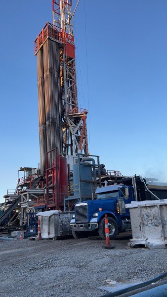 Dump truck parked beneath a drilling rig
