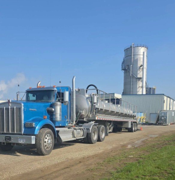Blue Kenworth tanker loading on a pad